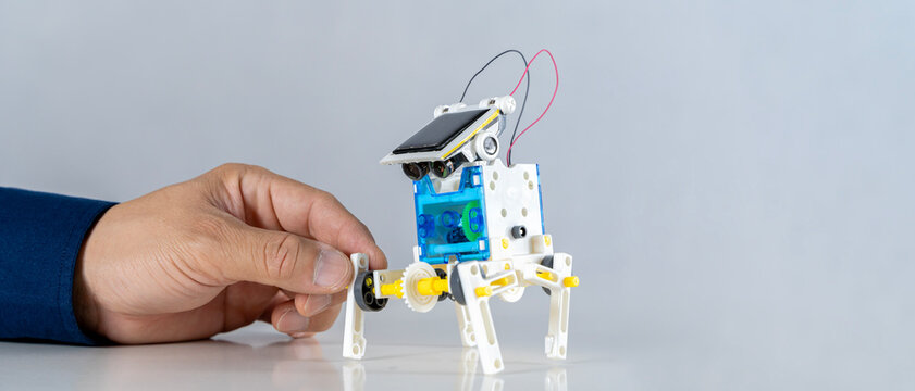 Man inventing building robots learning cars together in STEM class. Happy students, children learning together building robots in classroom.