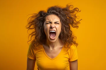 Fotobehang Portrait of an angry woman on a yellow background © frimufilms