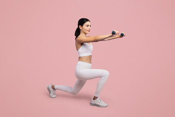 Fototapeta na wymiar Woman lunging with dumbbells, white attire, pink background