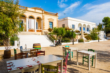 Taverna chairs with tables on square with typical Greek architecture in Plaka village, Milos island, Cyclades, Greece - obrazy, fototapety, plakaty