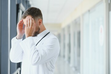 Naklejka na ściany i meble Sad doctor standing in hospital corridor