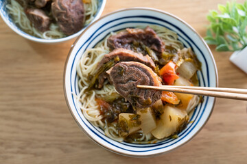 Beef noodle soup. Taiwanese famous food in a bowl on wooden table.