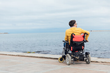 a special person with disabilities looks at the sea walk