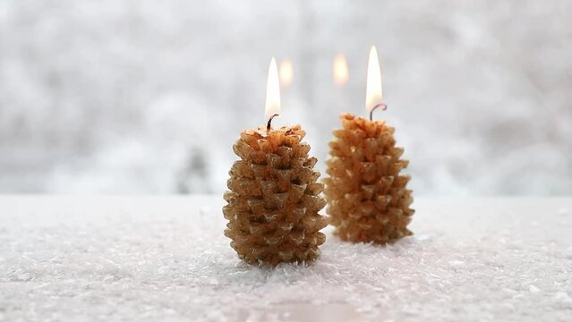 Spruce tree shape candles burning on white snowy background with winter landscape. Lot of copy space. Winter and Christmas products background.