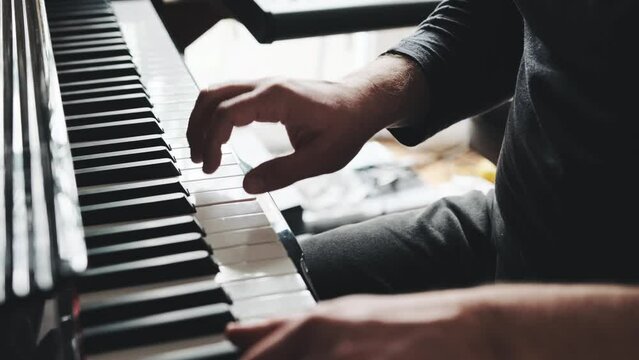 Man hands playing piano keyboard closeup and creating instrumental composition with professional sound. Musician perfomance with classical music on pianoforte