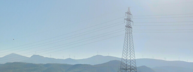 High voltage post or High voltage tower on background mountains with Wind turbines