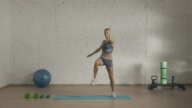 Healthcare and wellness advertisement concept. Athletic woman fitness coach doing elbow knee rise set for online classes. HDR BT2020 HLG material.