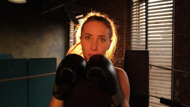 Women self defense girl power. Strong woman fighter punching with boxing gloves to camera. Healthy strong girl punching training punches looking concentrated straight. Fit body workout