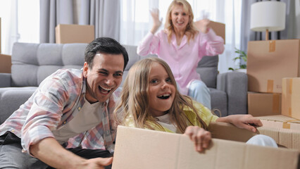 Happy family move into new house. Cute little girl ride inside box. Nice child have fun. Crazy...
