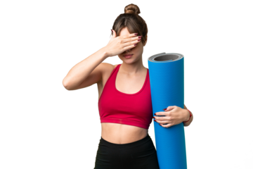 Young sport girl going to yoga classes while holding a mat over isolated chroma key background covering eyes by hands. Do not want to see something