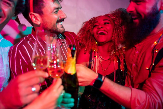 Friends dancing and drinking champagne at New Year party midnight countdown