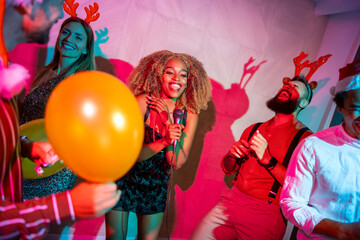 Friends dancing and singing karaoke at New Year party