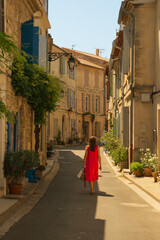 Woman in beautiful red dress walking in the historic southern town of Arles, southern France. 