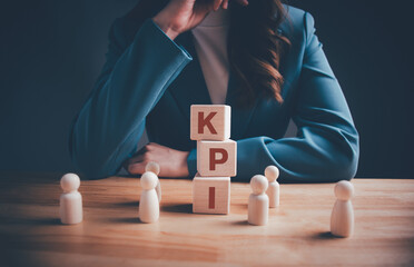 Businesswoman with KPI text on wooden blocks. KPI, Key Performance Indicator. Business goals,...