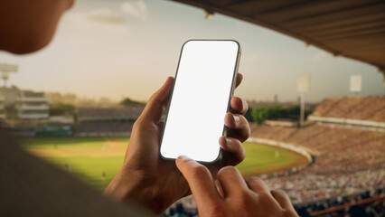 Indian male fan using phone during cricket game on a stadium, making bet