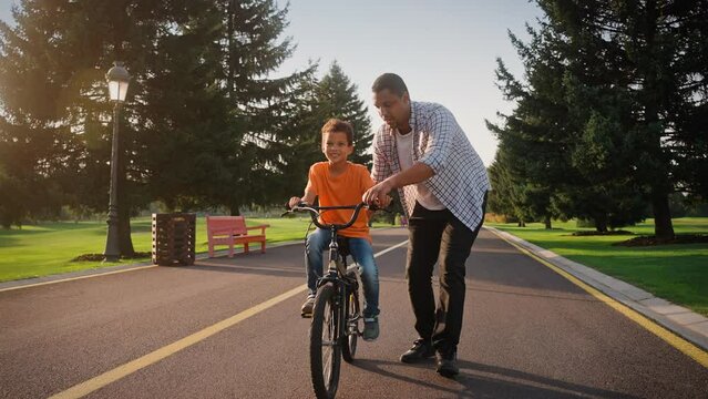 Dad giving instruction to son how to ride two-wheeled bike