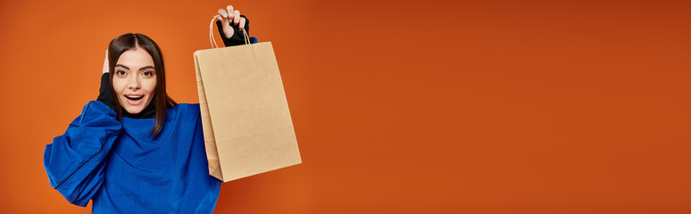 banner of excited woman in autumn attire holding shopping bag with black friday letters on orange