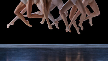 Cropped image of legs. Group of young people, ballet dancers in motion, in a jump, dancing against black background. Concept of classical and modern dance, beauty, creativity, art, theater