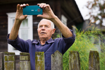 Senior man photographing with smartphone outdoors