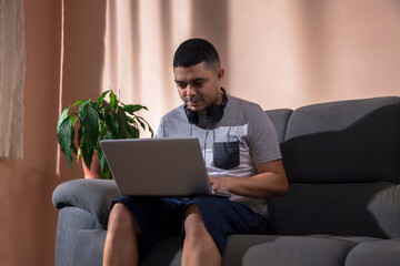 Man sitting on the couch with laptop on his lap while making a video conference call on the computer. Call concept. Computer concept.