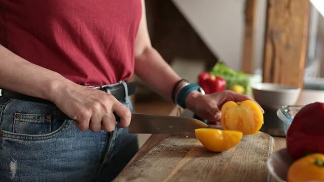 girl cutting a yellow tomato for salad on a cutting board in the kitchen