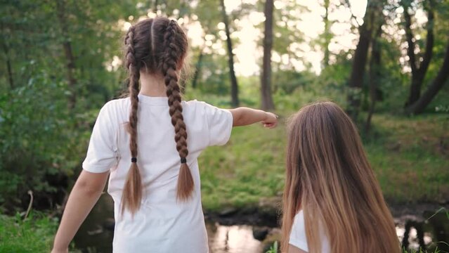 girl child plays with a group of friends in the forest in the park by the river. happy family dream content. girls child having fun in glare of the sun. girl with lifestyle braids