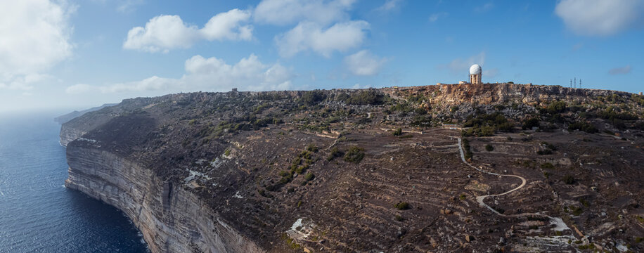 Aerial view of beautiful high cliffs along the coastline with a meteorological station facing the Mediterranean Sea, Dingli, Malta.
