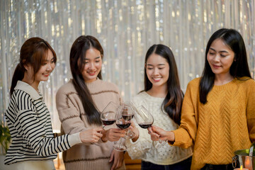 Cheerful friends enjoying home Birthday holiday party. Asian Friends cheering drinking red wine celebrating Christmas or New Year party