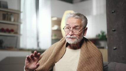 Confused gray haired man reading medical instructions or composition and refuses to take the drug at home Nervous senior male checking pills for ingredients and information and dissatisfied indoors