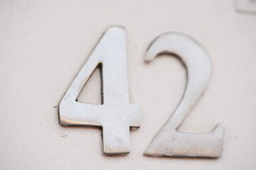 House number forty two (42) in silver painted text on a white door.