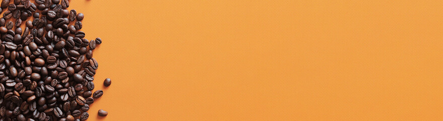 Roasted coffee beans on orange background, top view. Pile of halves of dark brown coffee beans, copy space