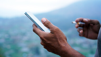 Closeup of person using phone. Hands of a business man holding cigarette while checking cellphone...