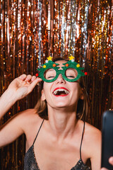 Happy woman taking selfie on smartphone celebrating New Year.