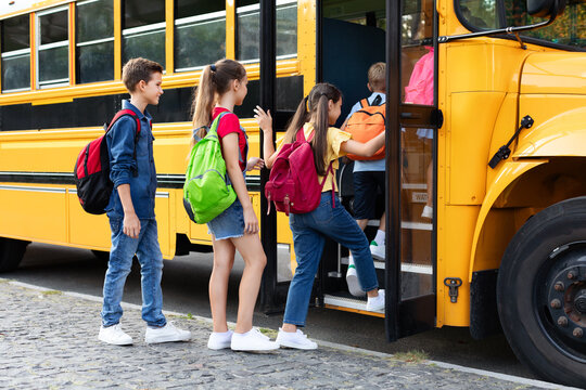 Group of happy excited children boarding yellow school bus