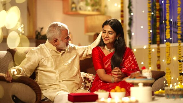 Indian father and daughter talking to each other during diwali celebrations while sitting on the sofa.Diwali decorations,wearing traditional dress.festival concept.looking good.
