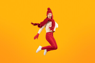 Fototapeta na wymiar Excited Lady In Knitted Hat And Gloves Jumping, Yellow Background