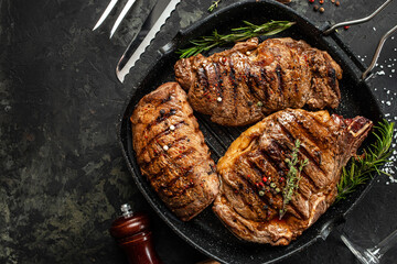 three beef steaks with grilled spices on a stone background. Restaurant menu, dieting, cookbook recipe top view.