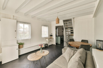 a living room with white walls and wood flooring in the center of the room there is a small table on the right side