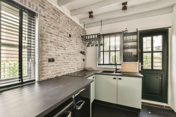 a kitchen with black counter tops and white brick wall in the background, there is an open window...