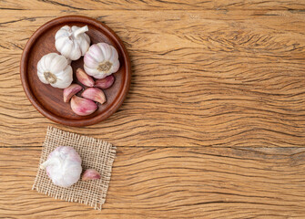 Garlic bulb and cloves on a plate over wooden table with copy space