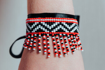 a bracelet of red and white beads and a black ribbon on the arm 