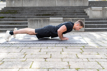 Fototapeta na wymiar Triangle push-up or diamond push done by a young man on concrete background outdoors