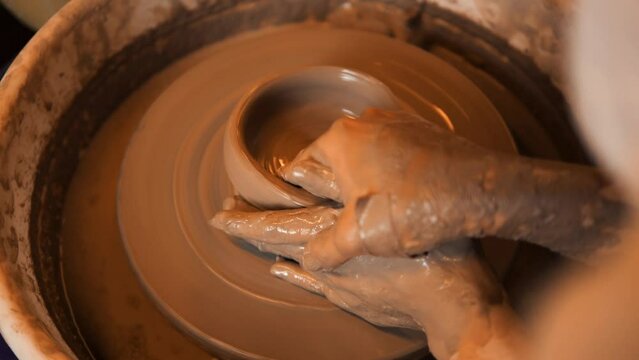 Young woman working on a potter's wheel, exploring the clay sculpting and handmade pottery process, wheel throwing workshop, high quality cinematic 4K slowmotion relaxation hobby concept footage.
