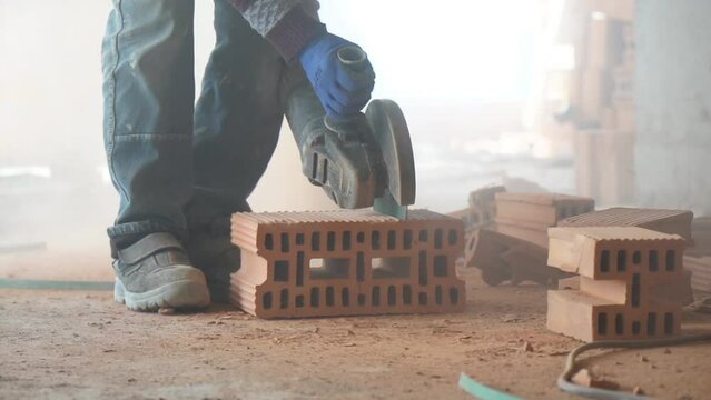 A construction worker expertly use a grinder to cut through bricks at construction site in slow motion