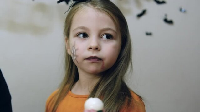 Little girl eating vampire eye candy. halloween party