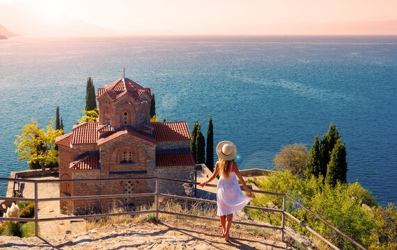 Young female in white dress and hat enjoying panoramic view of famous church,  Ohrid lake in Macedonia