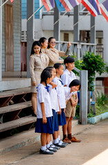 Vertical image of Asian students with uniform stand in a row in front of building and some girl...