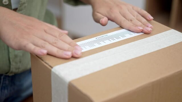 A woman customer labels a cardboard parcel with a barcode for a swift online shopping refund. 