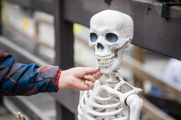 Smiling boy touching teeth you skeleton during Halloween.teeth
