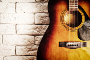 Grunge image of the old acoustic guitar in the interior with white brick wall. Musical instruments...